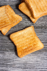 Several slices of toasted bread toasts on a wooden dark background
