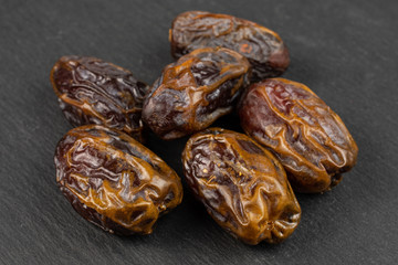 Group of six whole dry brown date fruit on grey stone