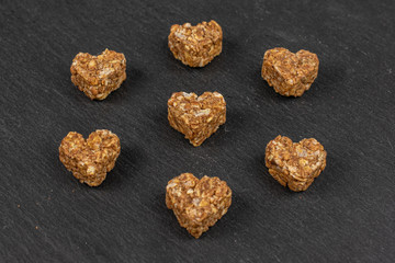 Group of seven whole healthy brown cereal heart with cocoa on grey stone