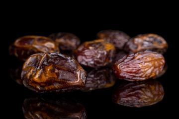 Lot of whole dry brown date fruit isolated on black glass