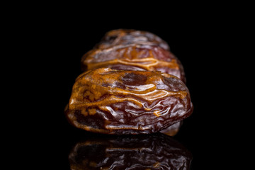 Lot of whole dry brown date fruit in line isolated on black glass
