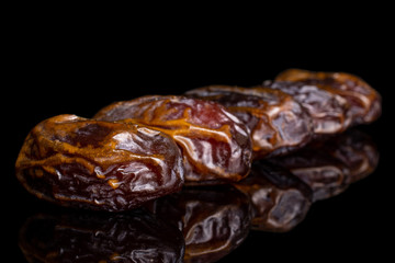 Lot of whole dry brown date fruit placed diagonally isolated on black glass