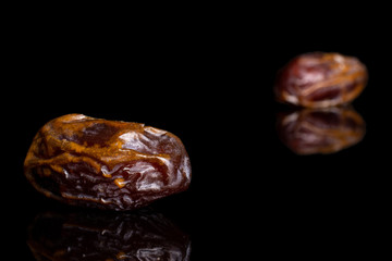 Group of two whole dry brown date fruit isolated on black glass