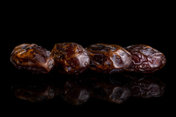Group of four whole dry brown date fruit isolated on black glass