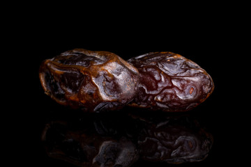 Group of two whole dry brown date fruit isolated on black glass