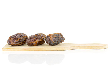 Group of three whole dry brown date fruit on small wooden cutting board isolated on white background