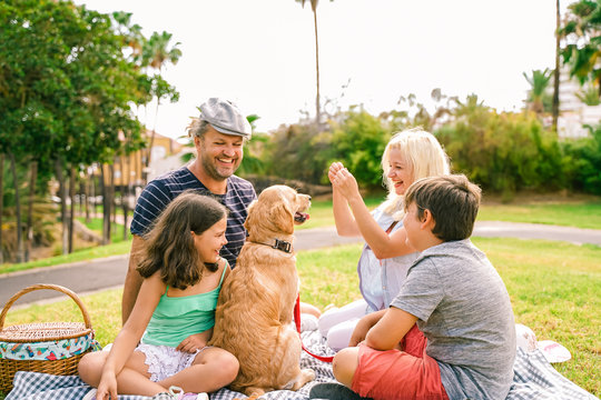 Happy family with their dog in a good summer day. The family playing with dog. Happy family doing picnic in the park . Travel , holidays and love concept - Image