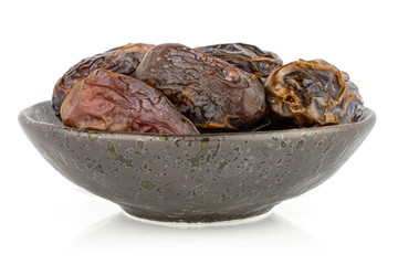 Group of five whole dry brown date fruit in dark ceramic bowl isolated on white background