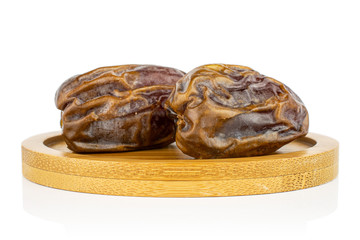 Group of two whole dry brown date fruit on bamboo coaster isolated on white background