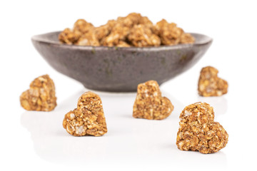 Lot of whole healthy brown cereal heart with cocoa in dark ceramic bowl isolated on white background