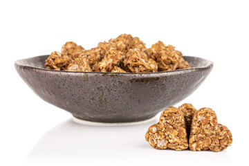 Lot of whole healthy brown cereal heart with cocoa in dark ceramic bowl isolated on white background