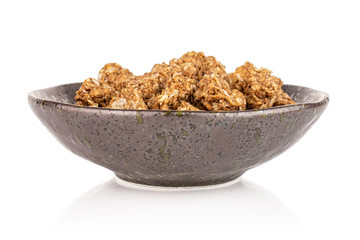 Lot of whole healthy brown cereal heart with cocoa in dark ceramic bowl isolated on white background