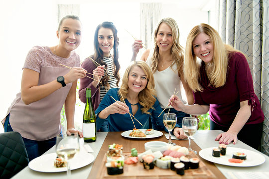 Group of attractive and funny woman eating sushi at home