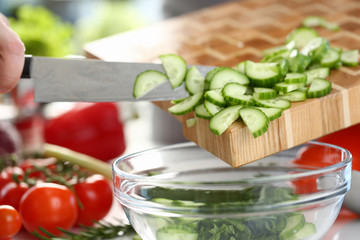 Organic Small Chopped Cucumber Slices Pouring Bowl. Pieces of Ripe Cuke on Wooden Board at Kitchen. Vegetable Green Dieting Salad. Healthy Vegetarian Diet Ingredient Horizontal Photography