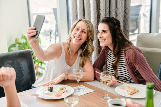 Two attractive mature people eating sushi at home taking photo