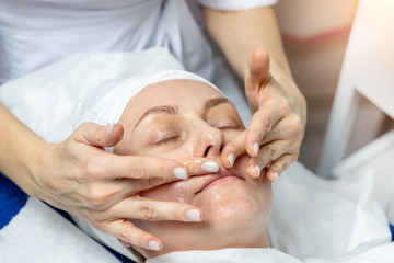 Obraz na płótnie Canvas Close-up beautician doctor hands making anti-age procedures, facial and head massage for mid-aged female client at beauty clinic. Cosmetologist doing skincare treatment .Health care therapy