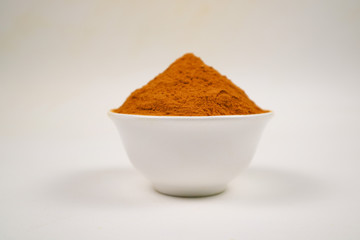 Turmeric powder in a separate white cup on a white background is used as a tonic for body and food ingredients.