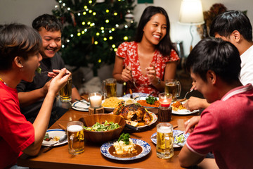 Group of Asian people have a dinner party and beer at home. They clink a glass of beer.