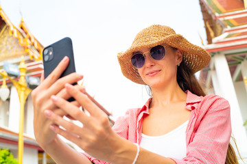 Tourist caucasian foreign backpack  women take selfie photo by smartphone wear sunglass in buddhism temple