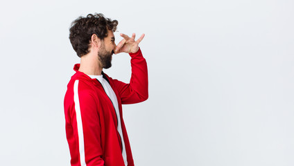 young bearded man back view feeling disgusted, holding nose to avoid smelling a foul and unpleasant...