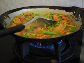 Stir fried pork in a pan on the gas stove in the house.