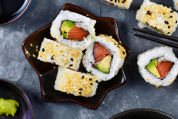 Sushi california rolls filed raw salmon fish, avocado, cream cheese and topped with sesame 