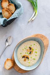 Cream soup with mushrooms champignon and potato in a bowl on gray background. Menu, recipe. Top view