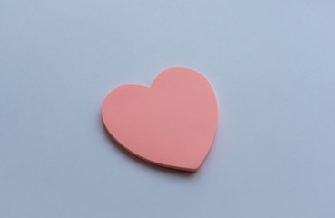 Pink heart-shaped sticky notes on white background. Concept of love, minimalism. Selective focus.