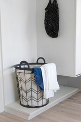  Laundry basket with dirty clothes in a white room corner.