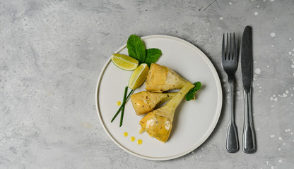 artichoke with olive oil, lemon and spices. typical Italian appetizer.  fresh and healthy artichoke plant. seasonal dish on a white craft plate. Italian cuisine recipe. selective focus
