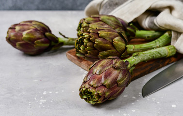 Fresh artichokes on a light stone table. . organic seasonal vegetables. artichoke recipe. selective...