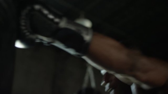 Close up of shirtless African American man hitting heavy bag in MMA gym