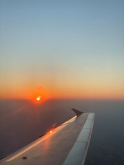 The air plane wing in the sky with sunset in the horizon
