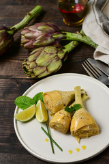 Artichoke seasonal appetizer with olive oil, mint and lime. on a white craft plate. Menu of seasonal vegetables. starter dish in Italian restaurant. top view, selective focus