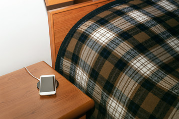 Mobile smart phone charging wirelessly by sharing battery via device in bedroom.