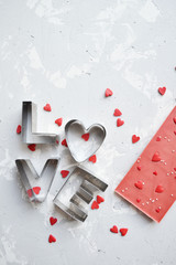 clippings from the word love are laid out from left to right with a silk scarf on a dirty gray background