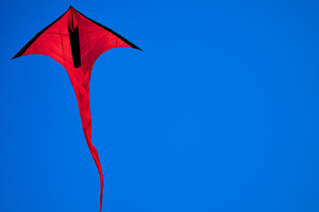 Red, arrow shaped kite in the blue skies