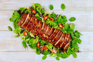 Cuts pork loin fillet serve with green salad and tomatos.