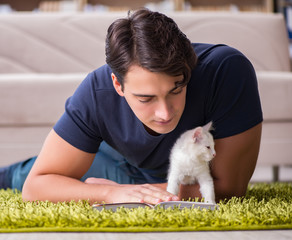 Young handsome man playing with white kitten