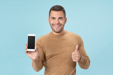 Happy young man with smartphone and showing ok gesture