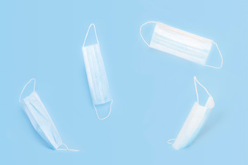 Medical masks with rubber ear straps flying on blue background. Protection concept from bacteria.