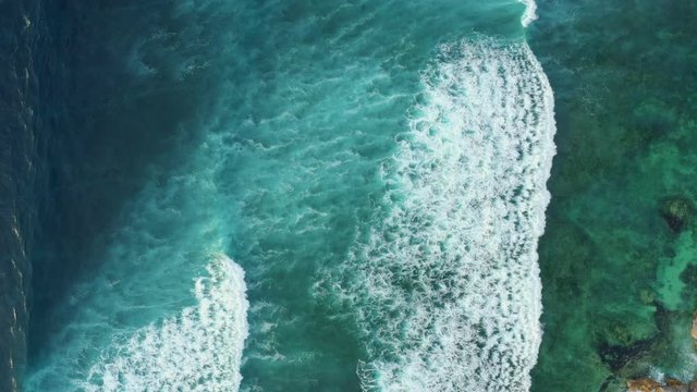 Aerial top down view of giant ocean waves crashing and foaming.