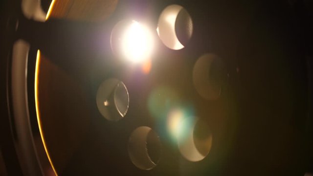 Abstract view of a cinema reel as the projector lights shine through the reel as it rotates.