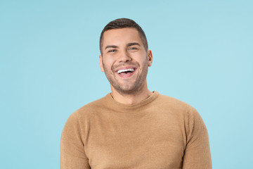 Laughing handsome guy in sweater isolated on blue background