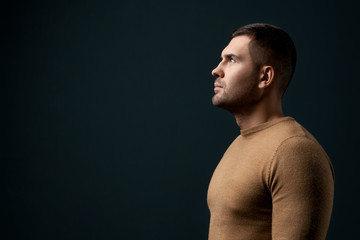 Portrait of handsome young man in dramatic light over dark background. Fashion photo