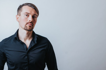 Fototapeta premium Photo of a handsome man with a coolly stylized scrub and hairstyle. Photo taken in a photo studio on a gray background. The man tries to express his emotions with gesticulation and mimics.