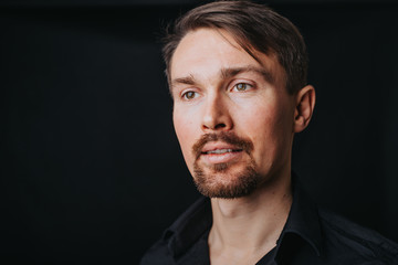 Fototapeta premium Handsome man. Photo in a photo studio on a black background. A young man expresses his emotions with expressions, gesticulation and attitude.