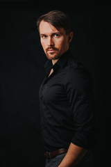 Handsome man. Photo in a photo studio on a black background. A young man expresses his emotions with expressions, gesticulation and attitude.