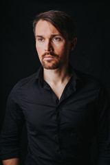 Handsome man. Photo in a photo studio on a black background. A young man expresses his emotions with expressions, gesticulation and attitude.
