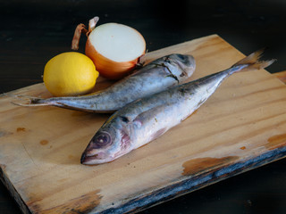 Two raw mackerels on a wooden board